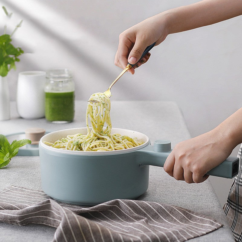 Person serving spaghetti from a blue pot with a green sauce.
